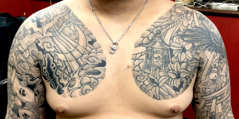 和彫り両腕胸に「月と太陽と風波雲影と、百合と灯籠と八咫烏と鳥居」の刺青