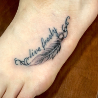 足の甲に羽のスモールタトゥーとテキストタトゥー
