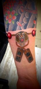和彫り腕に「虎の頭と札が付いた数珠」の刺青