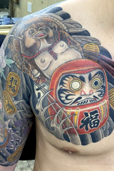 和彫り腕胸に「達磨と狸」の刺青