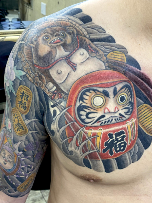和彫り腕胸に「達磨と狸」の刺青