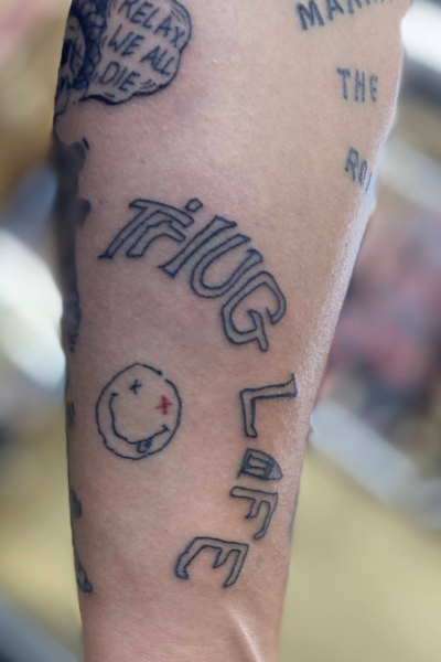 腕に「落書き風文字」のタトゥーと「スマイルマーク」のスモールタトゥー